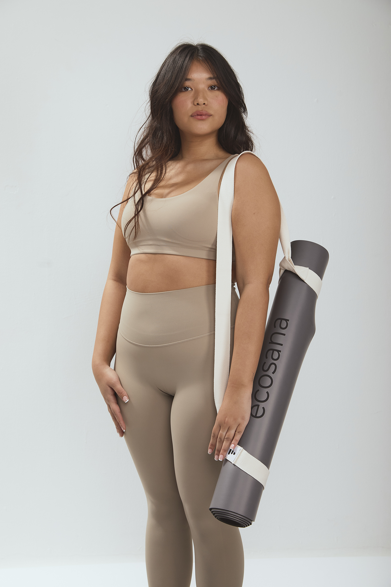 דוגמנית מחזיקה מזרן יוגה עגול מחומרים טבעיים